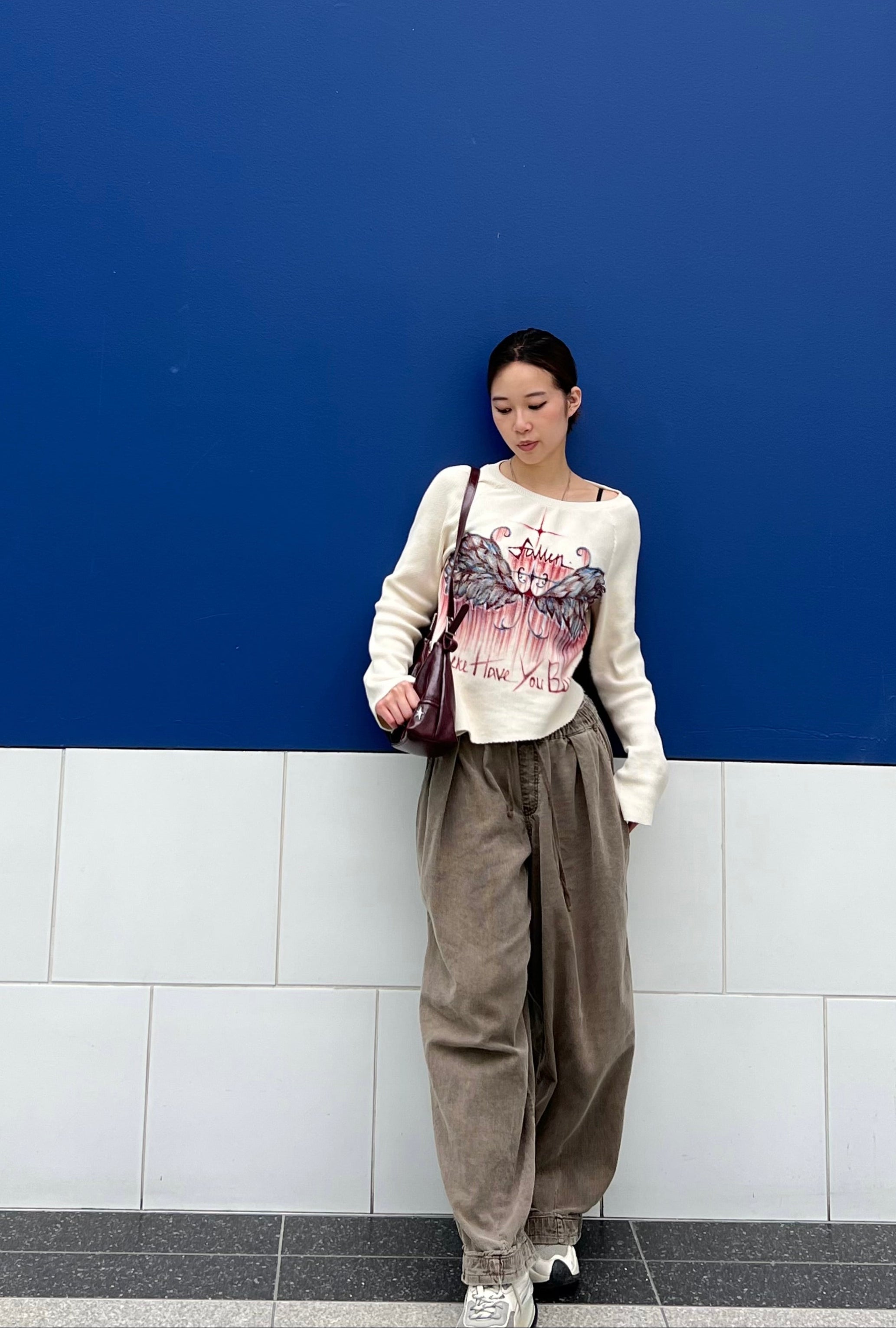Person leaning against a blue wall with a white tiled base.